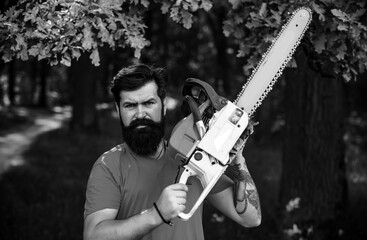 Wall Mural - Lumberjack on serious face carries chainsaw. Deforestation is a major cause of land degradation and destabilization of natural ecosystems. Man doing mans job.