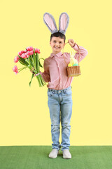 Poster - Cute little boy with bunny ears, Easter eggs and tulip flowers and on yellow background