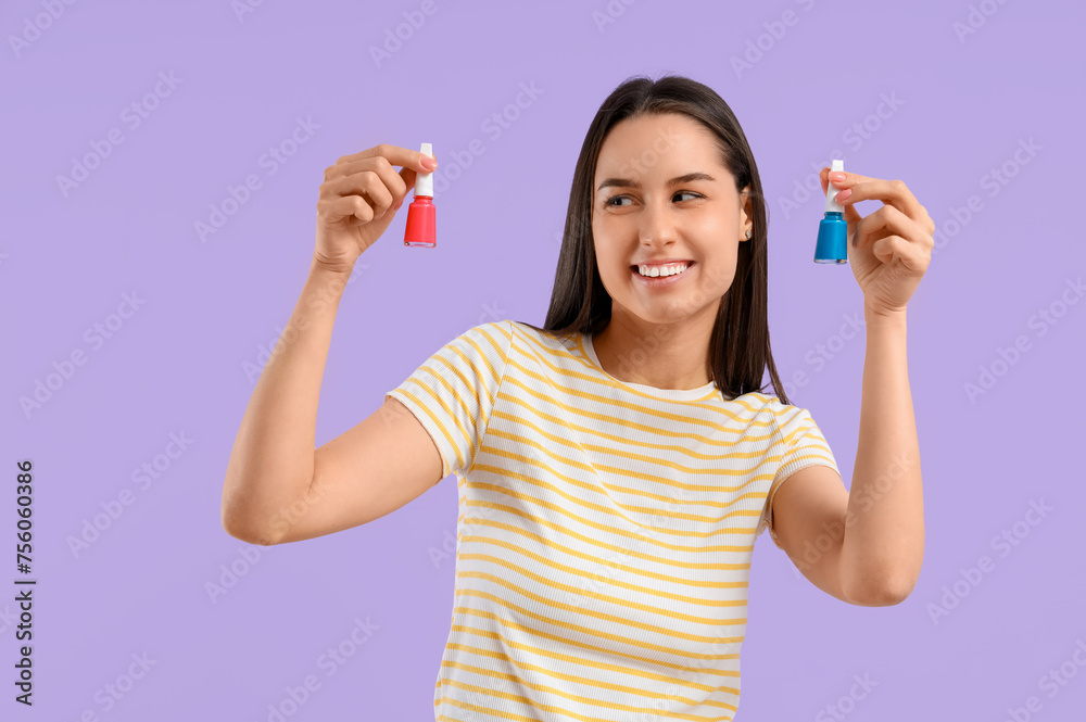 Young woman with nail polishes on lilac background