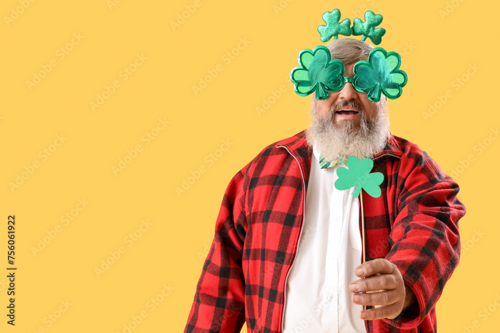 Mature man with clovers on yellow background. St. Patrick's Day celebration