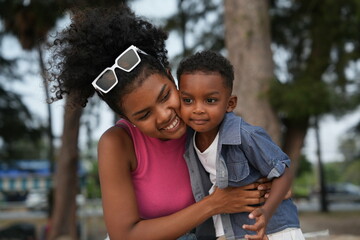 Wall Mural - Mixed race African and Asian mother and boy is playing at the outdoor area. smiling happy family have fun running on the beach. portrait of mom and kid lifestyle with a unique hairstyle.