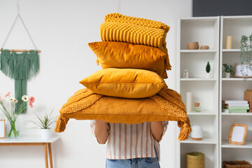 Sticker - Woman holding stack of pillows with folded warm plaid in room