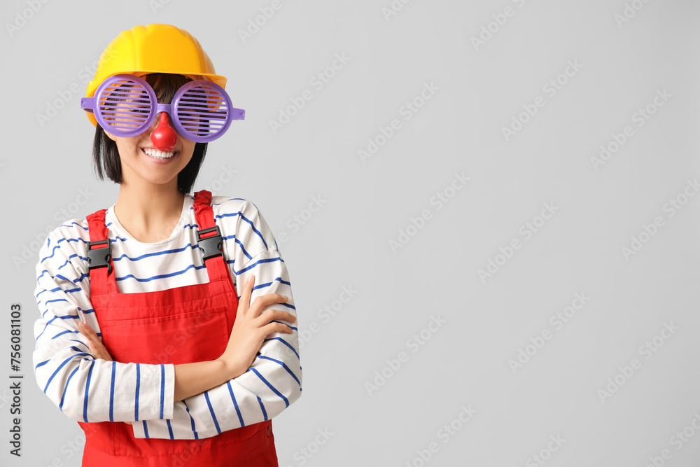 Young female builder with hardhat and funny glasses on white background. Fool's day