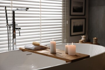 Wall Mural - Wooden tray with burning candles, towel and brush on bathtub in bathroom