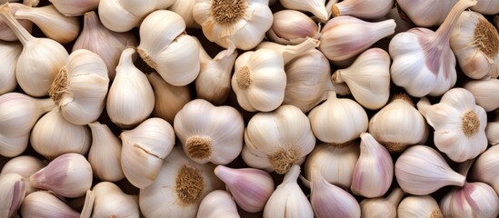 Poster - A stack of fresh garlic bulbs rests on a table, ready to be used as an essential ingredient in a delicious recipe. This natural food adds flavor to dishes and enhances cuisine with its pungent aroma