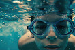 a kid in goggles and cap swimming underwater in pool