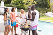 Diverse group of friends enjoying a barbecue by the pool, sharing laughter and drinks