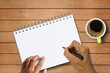 © nilawan - Hand holding pen and notebooks with coffee cup on wood table
