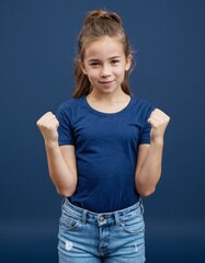 a young preteen or teen girl is standing with her arms raised in the air, wearing a blue shirt and b