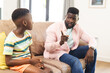 © Wavebreak Media - African American father in a pink shirt appears to be giving advice to a young son