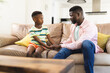 © Wavebreak Media - African American father and son sit on a sofa, holding hands and engaging in a serious conversation