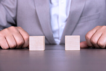 A businessman holds two wooden cubes with empty space for icons, free space for letters, numbers, symbols or labels.