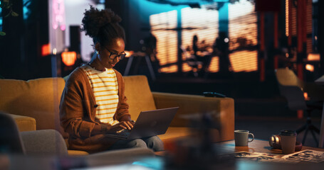Poster - Portrait of Black Creative Young Woman Working on a Laptop in Creative Office at Night. Female Team Lead Smiling While Checking her Team Performance Data, Sending Emails of Feedback