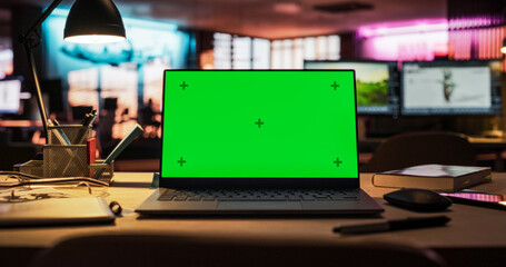 Leinwandbilder - Laptop Computer Standing on a Wooden Desk with a Green Screen Chromakey Mock Up Display. Creative Office Working Station for Game Developer and Graphic Designer in Creative Agency