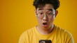 23-year-old asian guy with glasses, wearing yellow shirt, close up shot of surprised reaction to cellphone display