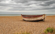The old boat on a shingle beach with a moody grey sky