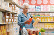 © StockPhotoPro - Senior customer comparing products at the supermarket