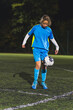 © PoppyPix - school-age Caucasian girl with blue uniform practicing football in a stadium at night. High quality photo