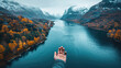  First-person perspective of a hand reaching out over a fjord surrounded by autumnal forests and snow-capped mountains.