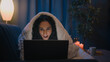 © Yuliia - Excited shocked Indian woman amazed wonder Hispanic girl shock surprised astonish stunned watching movie reading news in laptop social media addict at night evening home on couch under blanket cover