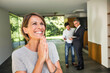  glückliche Frau in einer neuen Immobilie, Mann und Makler im Hintergrund im Haus, Bayern, Deutschland