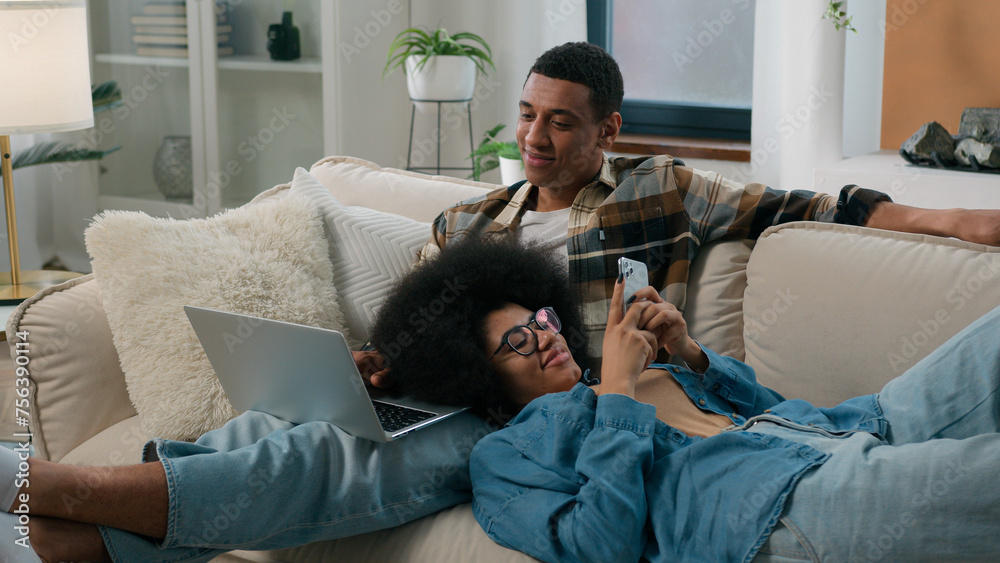 African American couple man with laptop computer sitting on couch home ...