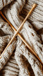 A close up of brown wooden knitting needles on a pile of grey and beige knitted fabric. The intricate pattern showcases the art of textile using woolen materials. Stories template background 