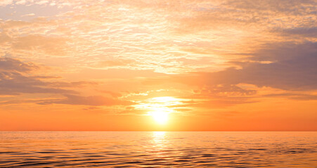 Wall Mural - Sunset sky background over sea in the evening with beautiful yellow sunlight reflection on water surface in golden hour time