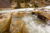 Fototapeta Na ścianę - Scenic spring waterfall in Ukrainian Carpathians. Beautiful river flow among huge brown rocks
