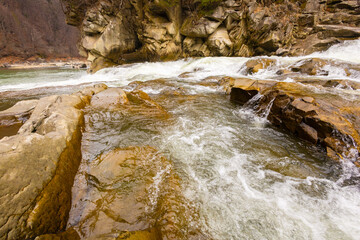 Scenic spring waterfall in Ukrainian Carpathians. Beautiful river flow among huge brown rocks