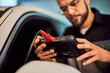 © bnenin - Focus on the mechanic's hands, holding a digital tablet, doing diagnostics on the car.