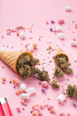 Wall Mural - Dry buds of medical marijuana lie on waffle ice cream cones on a pink background.  There are candies and marshmello around.  Alternative medical cannabis treatment