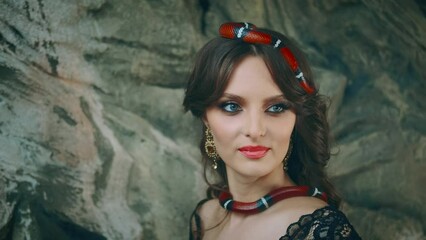 Wall Mural - Closeup fantasy portrait beautiful cute gothic brave woman mistress snakes. Brunette lady, red boa constrictor crawls through loose long hair. Evening makeup natural cosmetics, healthy skin blue eyes