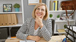© Krakenimages.com - Smiling middle-aged blonde woman in glasses positioned in a modern office setting, exuding professionalism and confidence.