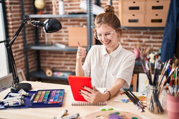 Sticker - Blonde young artist woman happily giving an 'ok' sign whilst looking at tablet screen in studio, radiating positivity and approval with her cheerful smile.