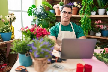 Sticker - Young hispanic man florist smiling confident using laptop at flower shop