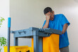 © Mdv Edwards - Middle aged janitor showing signs of stress and fatigue while pushing a cleaning cart down a building hallway. Fed up and exasperated with his job.