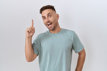 Poster - Hispanic man with beard standing over white background pointing finger up with successful idea. exited and happy. number one.