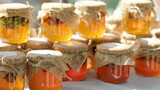 Fototapeta Paryż - Rows of jars of bright yellow orange honey at the outdoor market