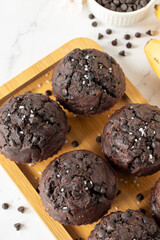 Wall Mural - Healthy double chocolate chip muffins with bananas on a wooden plate. Eating sweet vegan dessert or snack. Close-up. Top table view.