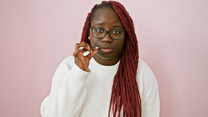 Sticker - African american woman with braids gestures for silence against a pink background