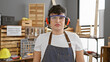 © Krakenimages.com - A young man wearing safety glasses and earmuffs stands confidently in a well-equipped carpentry workshop.
