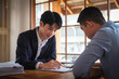 © wattana - Concentrated male insurance agent discuss paper policy terms conditions with his client at meeing.