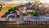 Fototapeta  - Antique town Porto, Portugal. Sunset sun over silhouettes skyline of porto city roofs houses along river