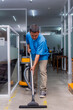© Mdv Edwards - A middle aged janitor cleans the concrete floor with a professional wet and dry vacuum cleaner.