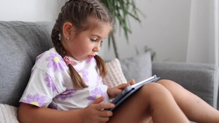 Adorable little girl use tablet at home. Five year old girl play games on tablet
