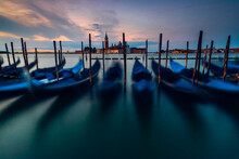 Row of gondolas moored with the Church of San Giorgio Maggiore in the distance at sunrise, Venice, Veneto, Italy