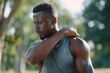A man injured his shoulder during a fitness class, an African-American man injured himself while jogging in the park, stretches his arm and massages his sore muscles, Generative AI