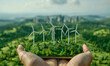 Point of view of businessman hand holding landscape with eco wind turbine