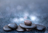 Fototapeta Kwiaty - Black spa stones on the gray table background.